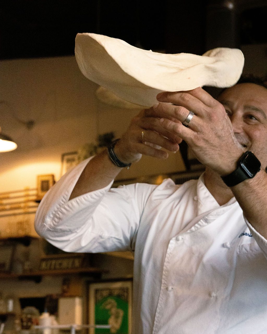 Charlie Accivatti tossing pizza dough in the kitchen
