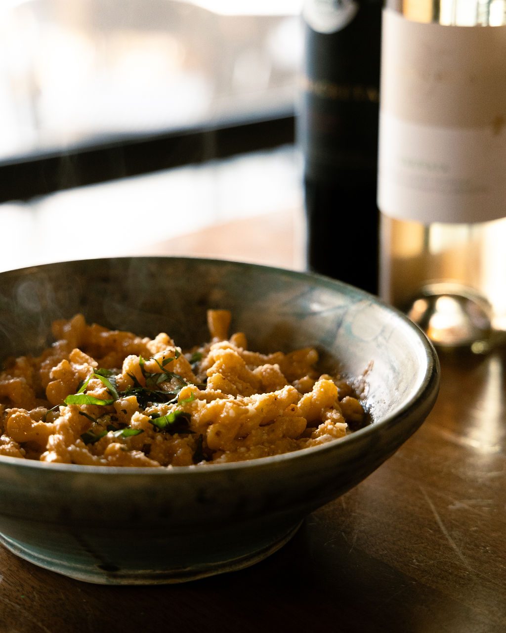 A steaming bowl of pasta with basil