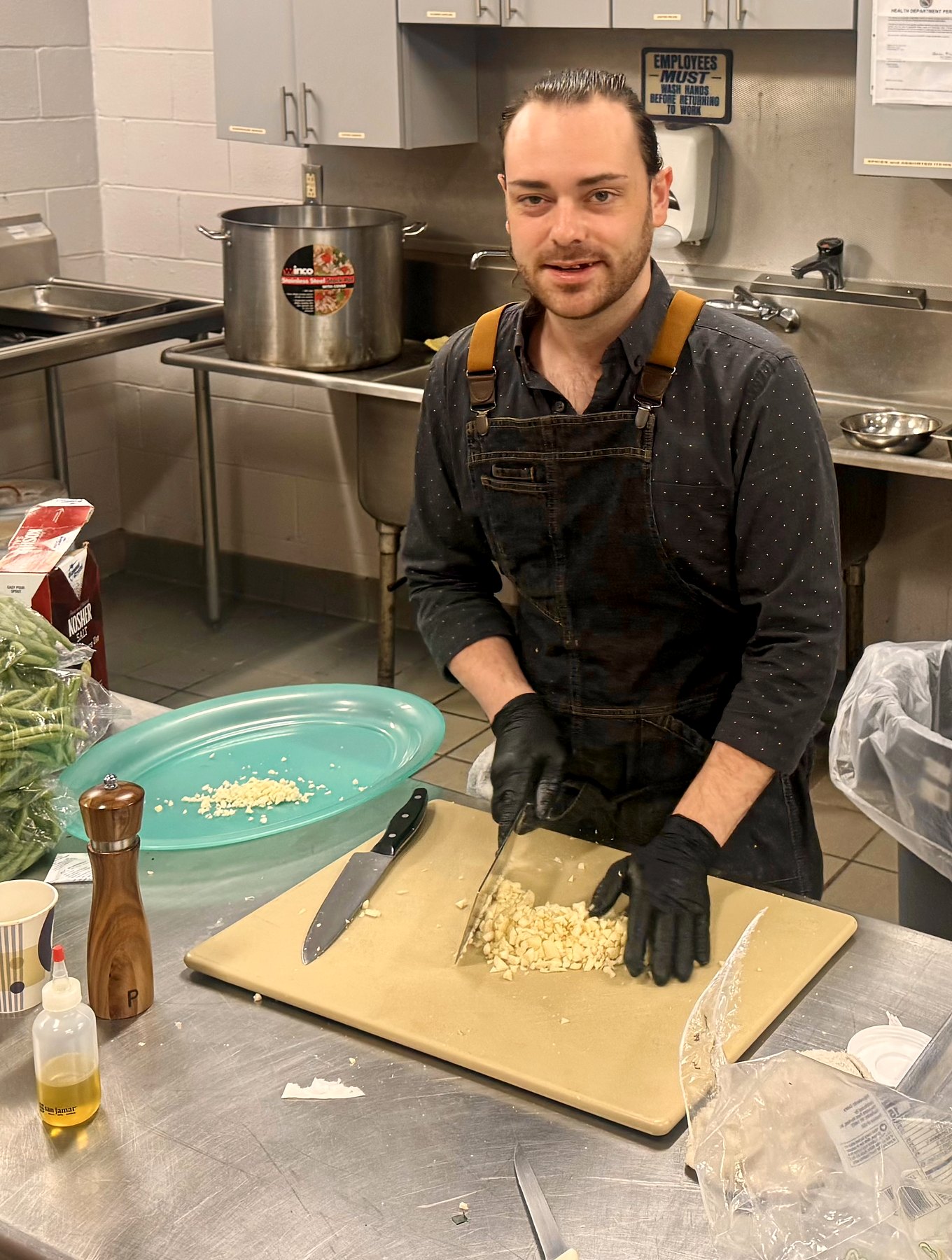 Team member prepping garlic in a commercial kitchen during a catered event.