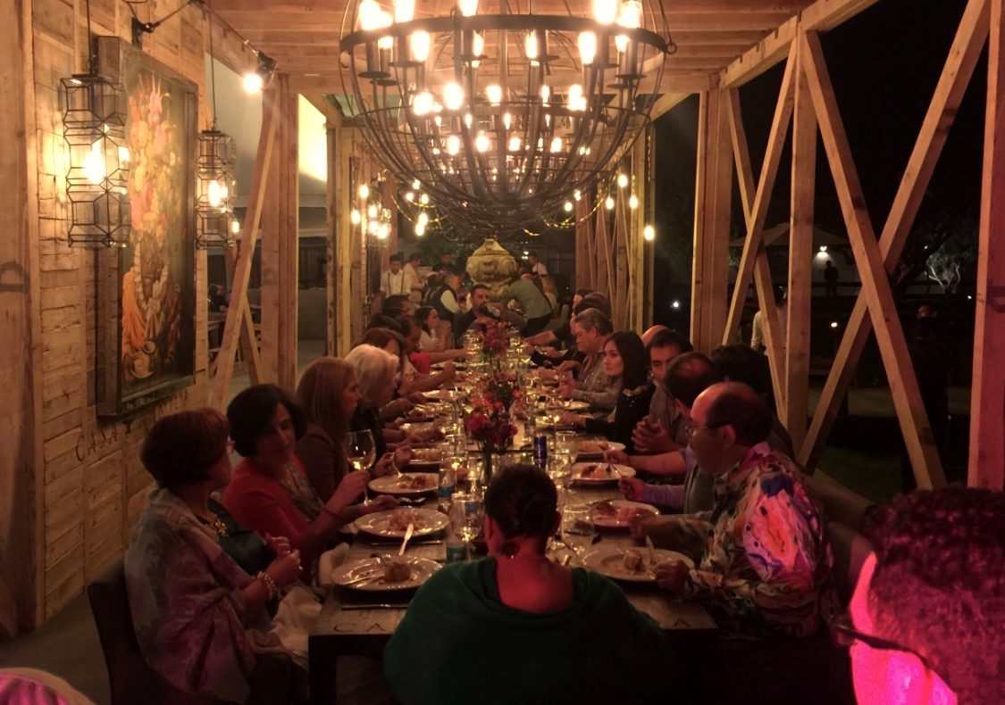 Guests at a long communal table under a chandelier