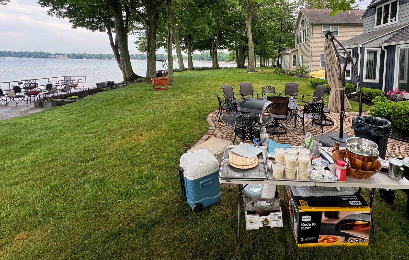 A lakeside pizza pop-up setup with the oven, prep table, and dough