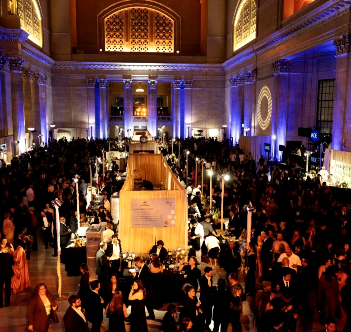 Black-tie crowd filling a grand hall under blue uplighting at a large-scale hospitality event