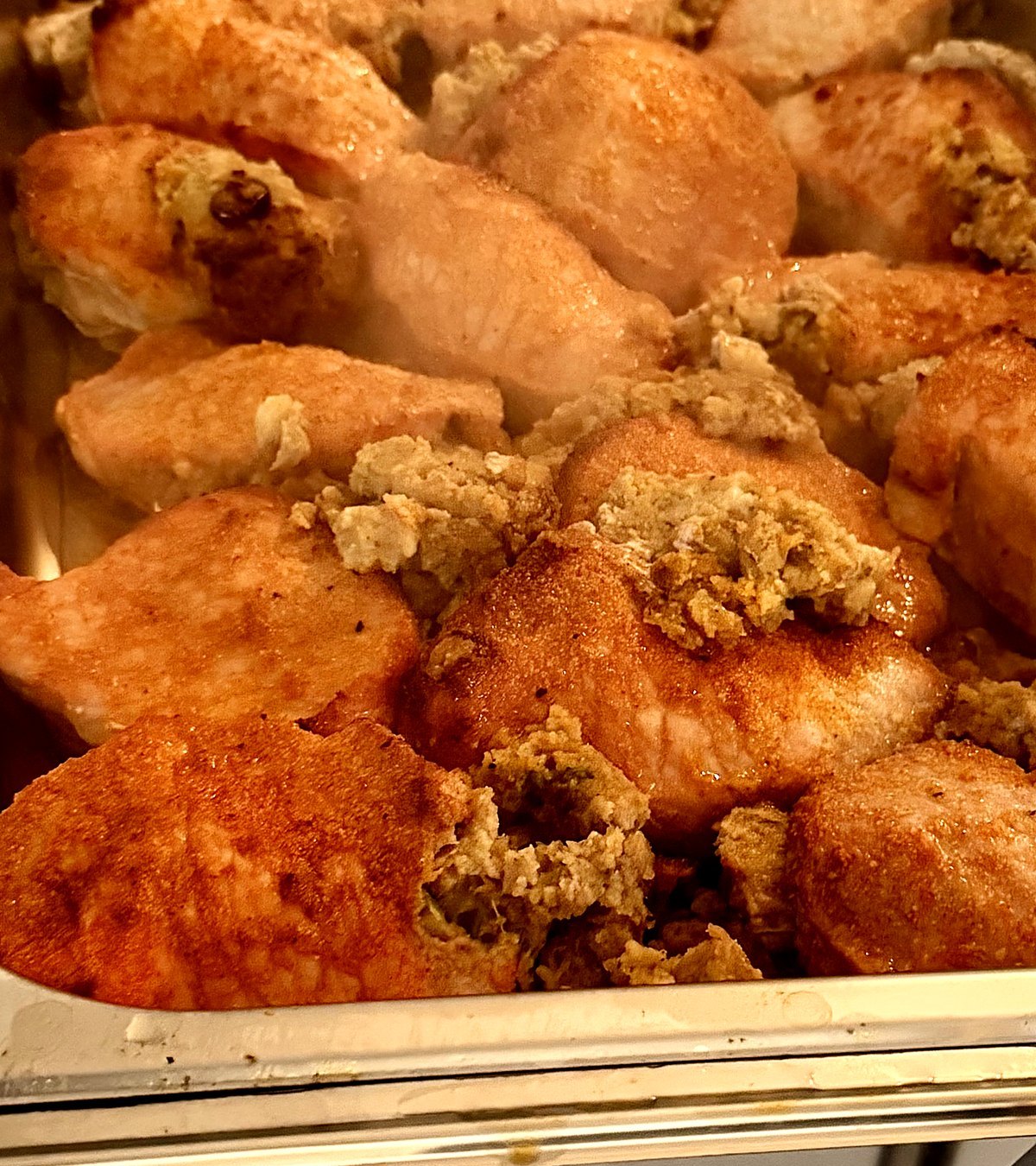 Close-up of golden stuffed pork chops with herb stuffing in a serving pan